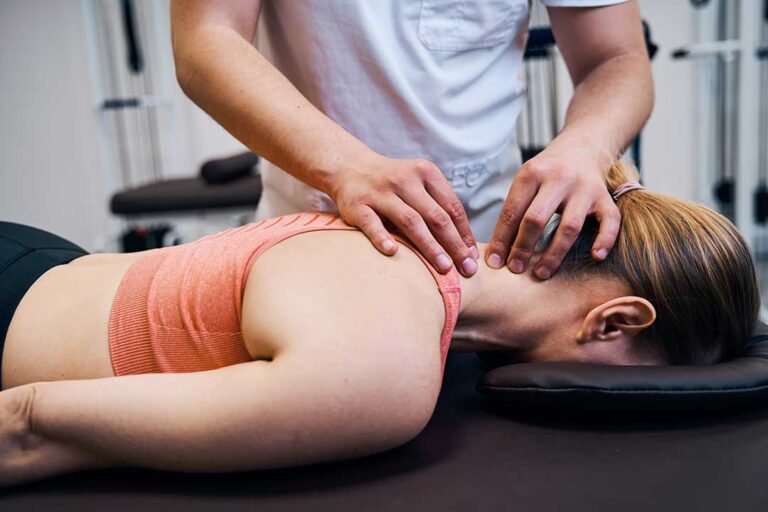 A chiropractor performing a back adjustment on a patient in a professional clinic setting.